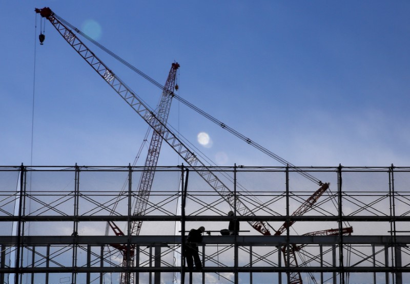 © Reuters. File picture of men working on a scaffolding as cranes are silhouetted against the sky at a construction site in Tokyo