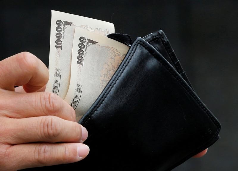 © Reuters. A man holds Japanese 10,000 Yen bank notes in front of a bank in Tokyo