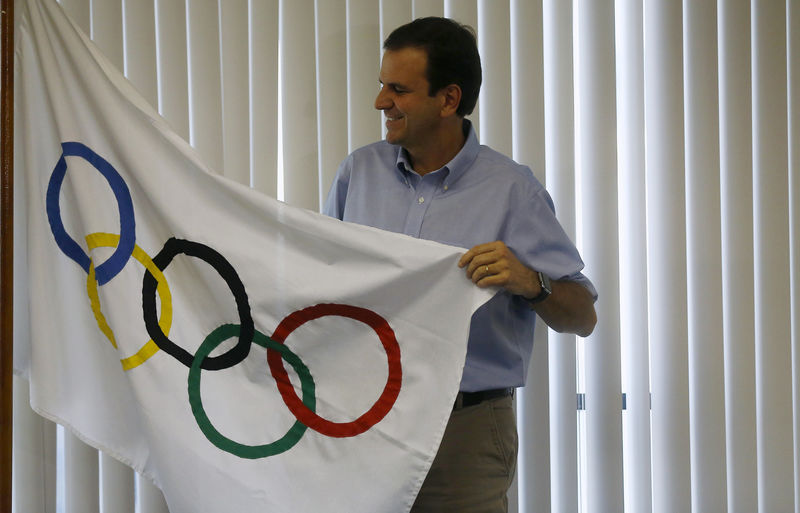 © Reuters. FILE PHOTO - Paes poses with an Olympic flag at his office after an interview in Rio de Janeiro