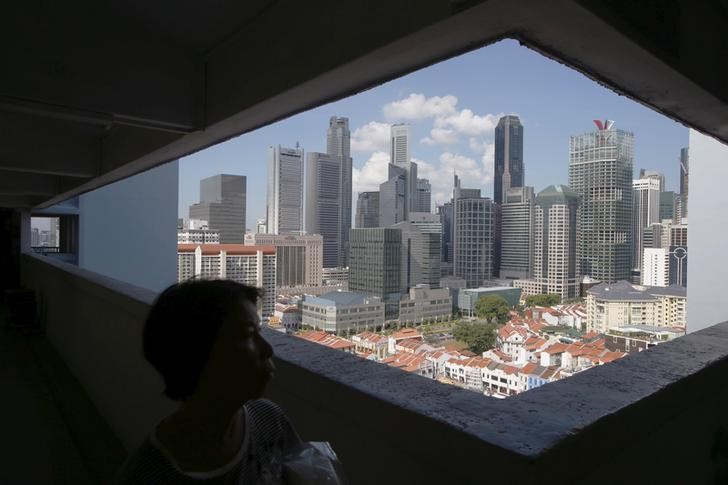 © Reuters. A woman passes the skyline of the central business district, in a public housing estate in Singapore