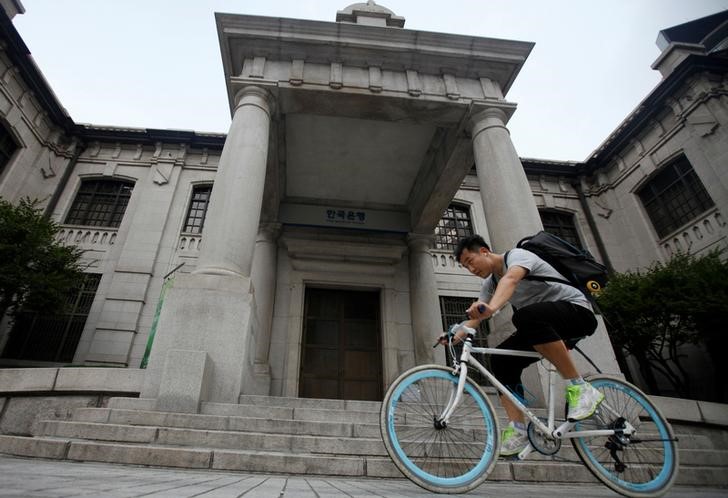 © Reuters. A man gets on a bicycle in front of the Bank of Korea in Seoul