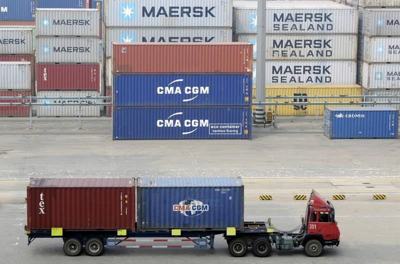 © Reuters. Truck carrying shipping containers travels at a port in Qingdao, Shandong province, China