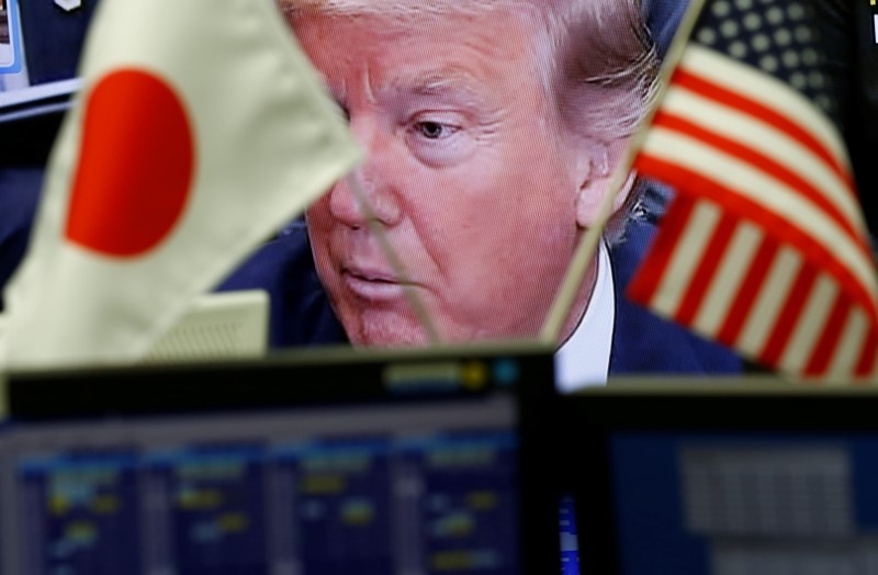 © Reuters. A TV monitor showing U.S. President Donald Trump is seen through national flags of the U.S. and Japan at a foreign exchange trading company in Tokyo