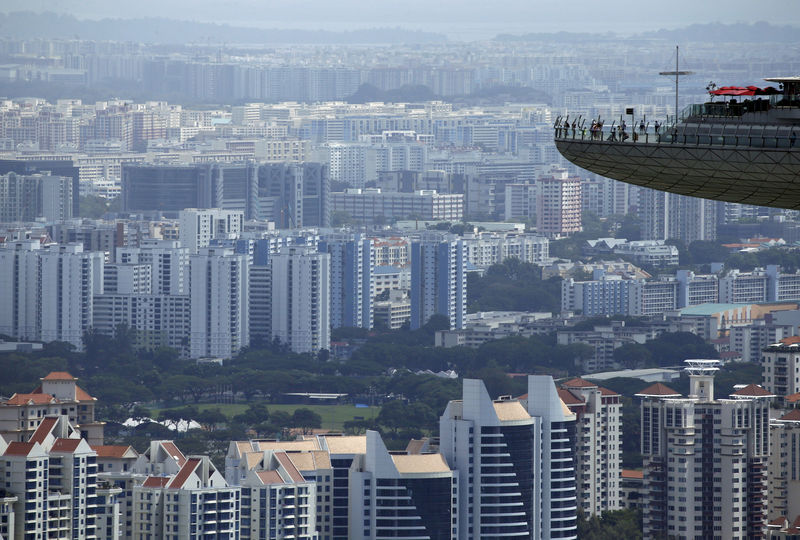 © Reuters. FILE PHOTO: People look out from the observation tower of the Marina Bay Sands amongst public and private residential apartment buildings in Singapore