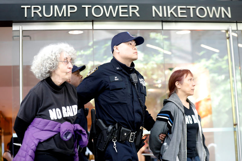 © Reuters. A New York City Police officer (NYPD) escorts protestors after making arrests for demonstrating in Trump Tower in New York