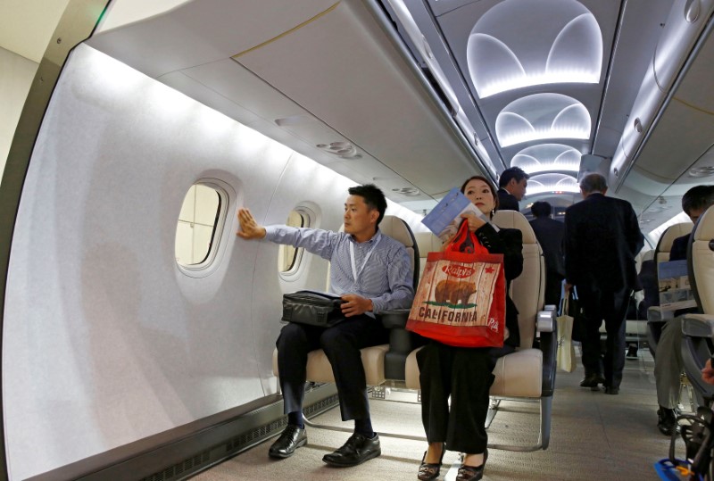 © Reuters. FILE PHOTO: Visitors sit inside a model of Mitsubishi Regional Jet's cabin during Japan Aerospace 2016 air show in Tokyo