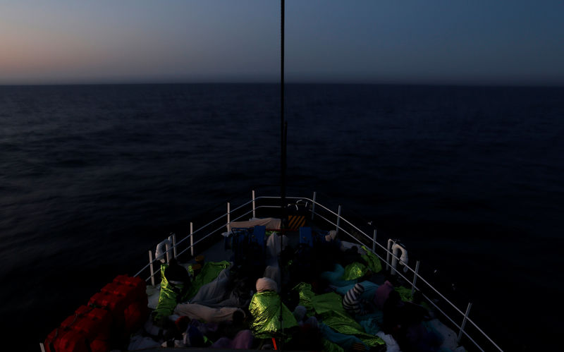 © Reuters. Migrants rest on the Malta-based NGO Migrant Offshore Aid Station (MOAS) ship Phoenix after being rescued in the central Mediterranean off the Libyan coast, as the ship makes its way towards Italy at dusk