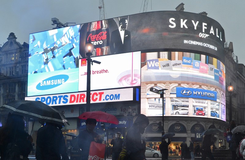 © Reuters. Shoppers pass an advertisement for the forthcoming James Bond film, Skyfall, on the electronic screens at Piccadilly Circus in central London