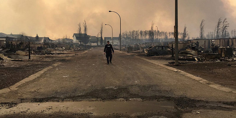 © Reuters. FILE PHOTO -- A Mountie surveys the damage on a street in Fort McMurray Alberta