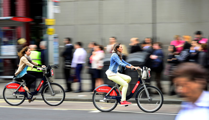 © Reuters. FILE PHOTO - Commuters cycle past a bus queue outside Waterloo Station in London