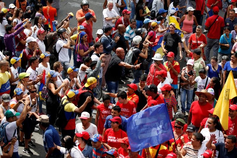 © Reuters. Partidarios (de rojo) y opositores al gobierno del presidente Nicolás Maduro discuten durante una marcha en Caracas