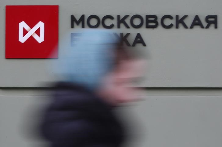 © Reuters. Woman passes by a sign outside the office of Moscow Exchange