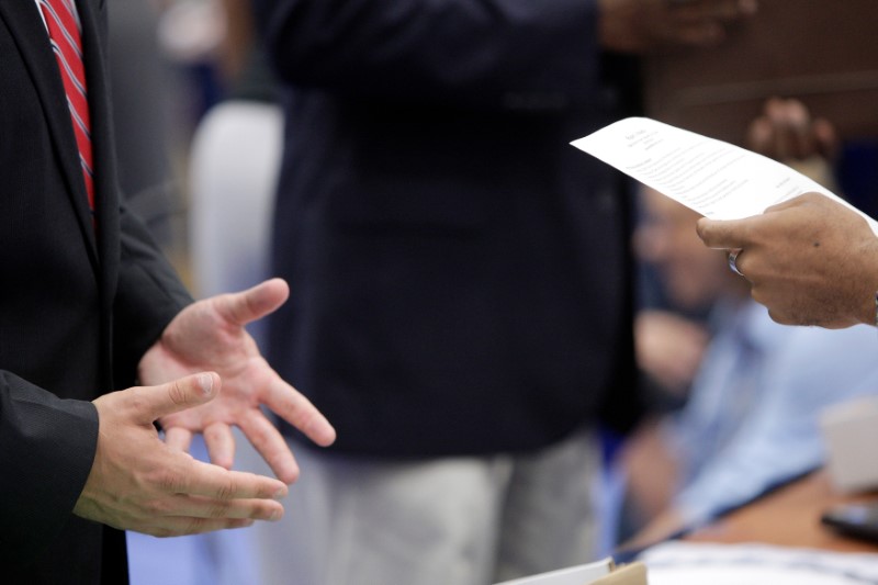 © Reuters. A job seeker talks with a corporate recruiter as he peruses the man's resume at a Hire Our Heroes job fair in Washington