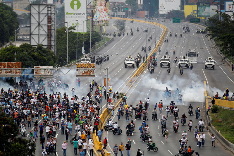 © Reuters. Demonstrators run away from tear gas during clashes with police while rallying against Venezuela's President Nicolas Maduro in Caracas