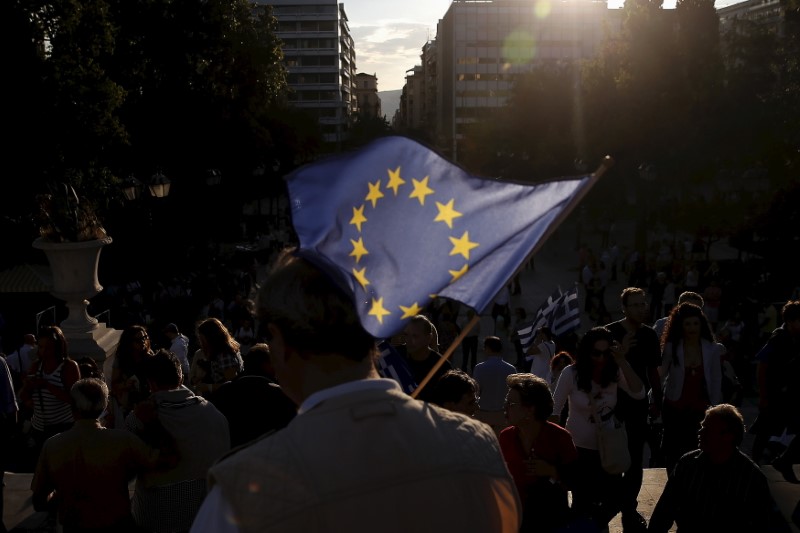 © Reuters. A pro-EU protester holds an European Union flag during a rally calling on the government to clinch a deal with its international creditors and secure Greece's future in the Eurozone, in Athens