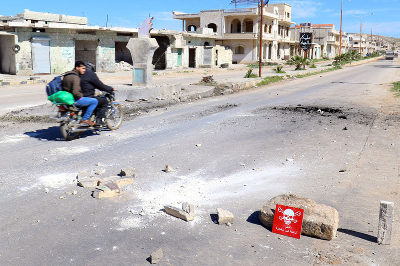 © Reuters. Men ride a motorbike past a hazard sign at a site hit by an airstrike on Tuesday in the town of Khan Sheikhoun in rebel-held Idlib