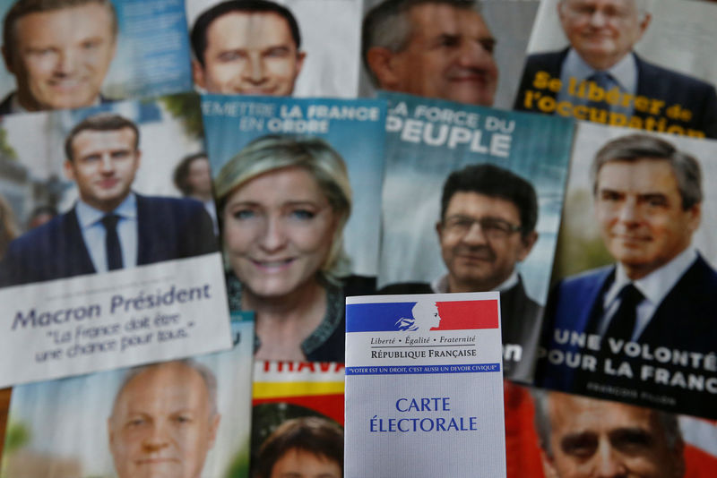 © Reuters. A photo illustration shows a French voter card in front of pictures of the candidates for the French presidential election