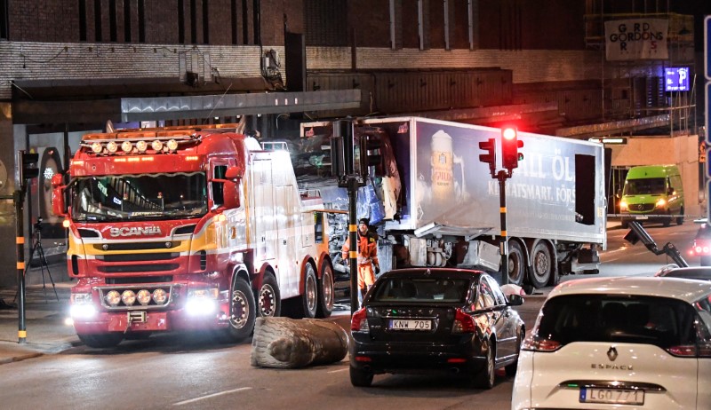 © Reuters. Tow trucks pull away the beer truck that crashed into the department store Ahlens after plowing down the Drottninggatan Street in central Stockholm
