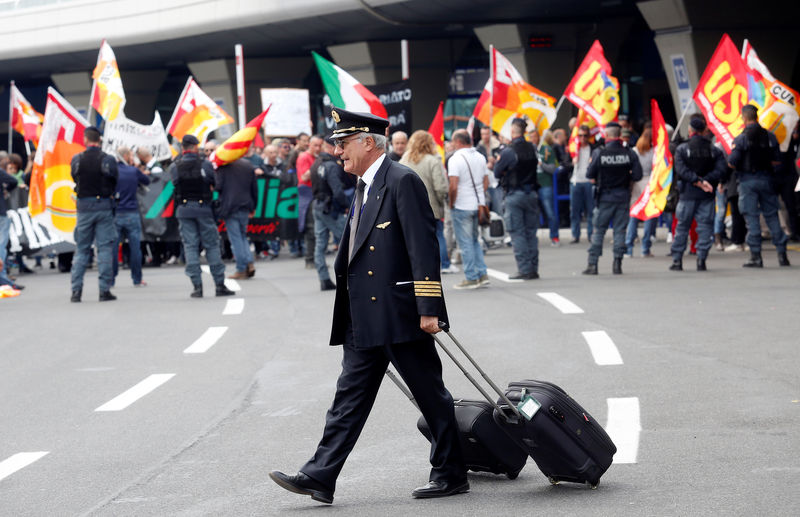 © Reuters. An Alitalia crew member walks past Alitalia employees who take part in a strike at Fiumicino international airport in Rome