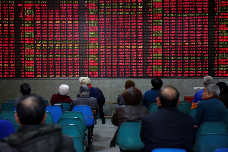 © Reuters. Investors look at an electronic board showing stock information on the first trading day after the New Year holiday at a brokerage house in Shanghai