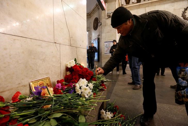 © Reuters. Мужчина оставляет свечу в память жертв взрыва в метро Санкт-Петербурга