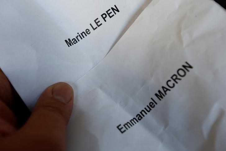 © Reuters. A voter holds ballots for candidates for French 2017 presidential election : Marine Le Pen and Emmanuel Macron before voting in the first round of 2017 French presidential election at a polling station in Tulle