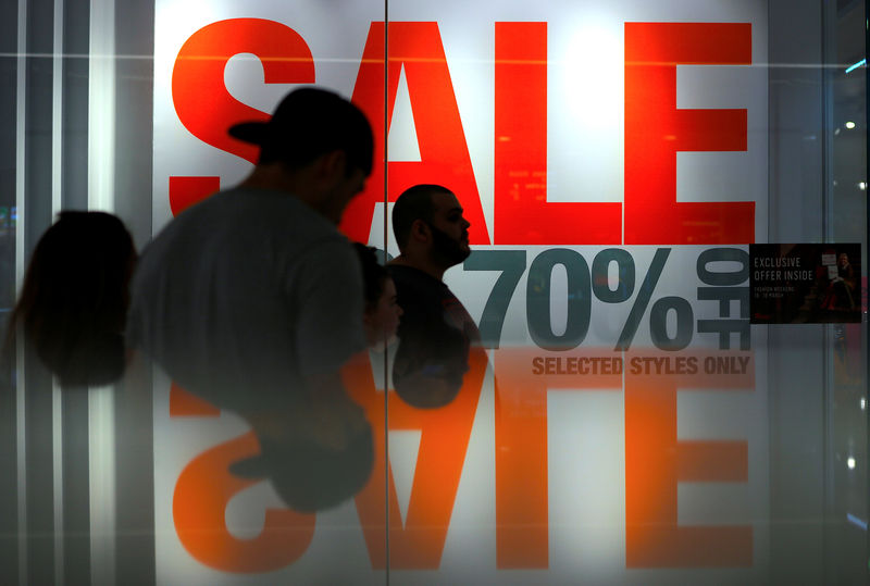 © Reuters. Shoppers walk past retail stores displaying sales posters in a shopping mall in central Sydney, Australia