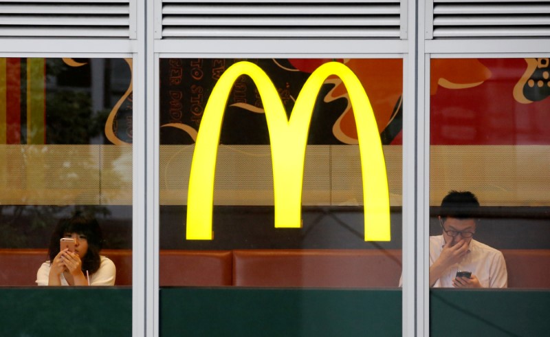 © Reuters. Customers using mobile phones, are seen through the windows of a McDonald's store in Tokyo