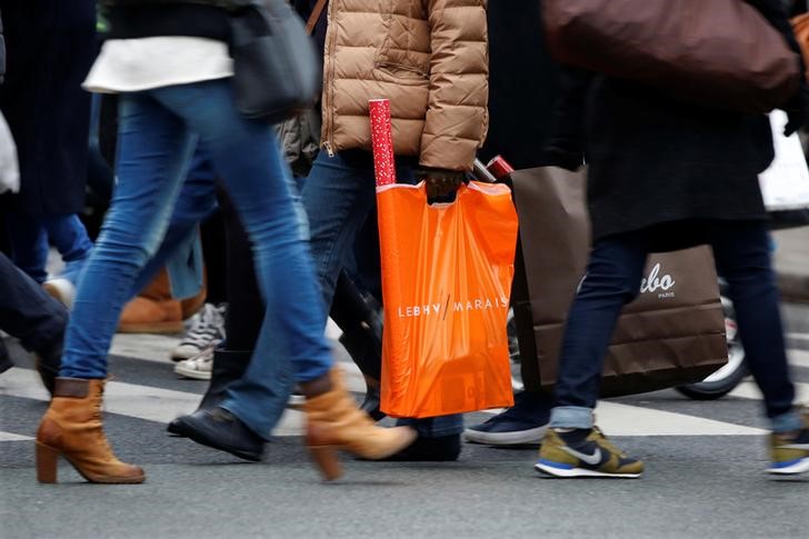 © Reuters. Shoppers carry bags as they take care of their last-minute Christmas holiday gift purchases outside department stores in Paris