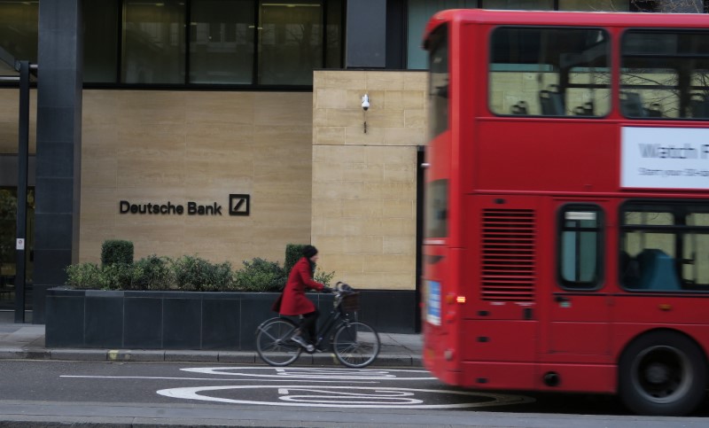 © Reuters. FILE PHOTO: A woman cycles behind a London bus as they pass by a Deutsche Bank building in the City of London