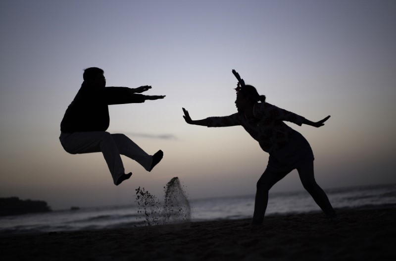 © Reuters. FILE PHOTO: Couple acts out a martial-arts move for a friend's camera as they wait to welcome the first sunrise of 2015 on Sydney's Bondi beach at dawn