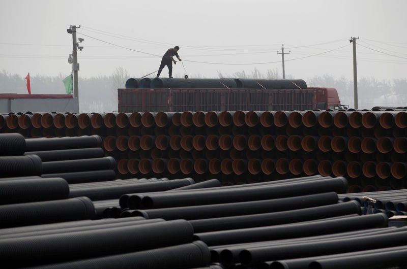 © Reuters. FILE PHOTO: A worker packs pipelines onto a truck at a local plastic pipe factory in Donghegang village on the outskirts of Xiongxian county