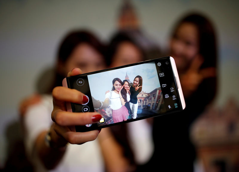 © Reuters. FILE PHOTO: Models pose for photographs with a LG electronics' new V20 premium smartphone during its unveiling ceremony in Seoul