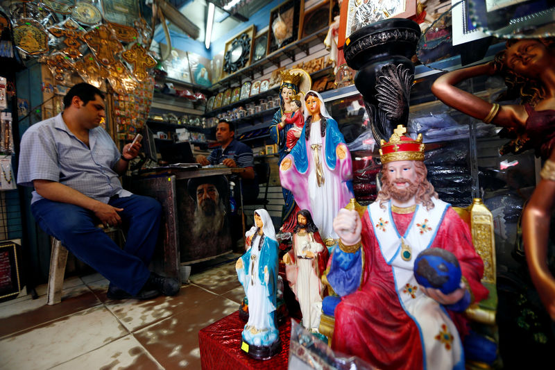 © Reuters. Men sit inside a Christian souvenir shop ahead of Pope Francis’ visit in Cairo