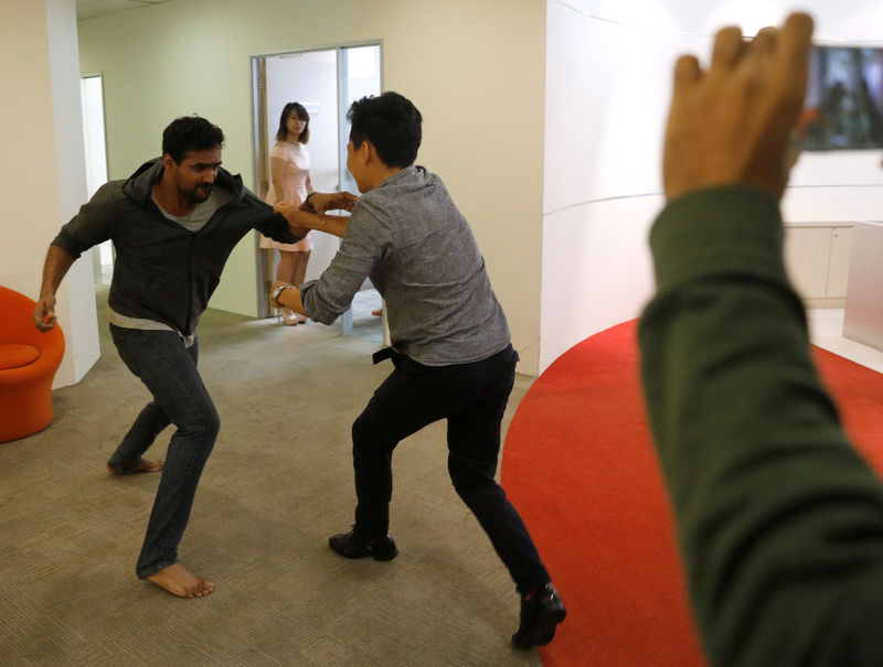 © Reuters. Graymatics employees pretend to fight as they record footage to be used to "train" their software to watch and filter internet videos for violence, at their office in Singapore