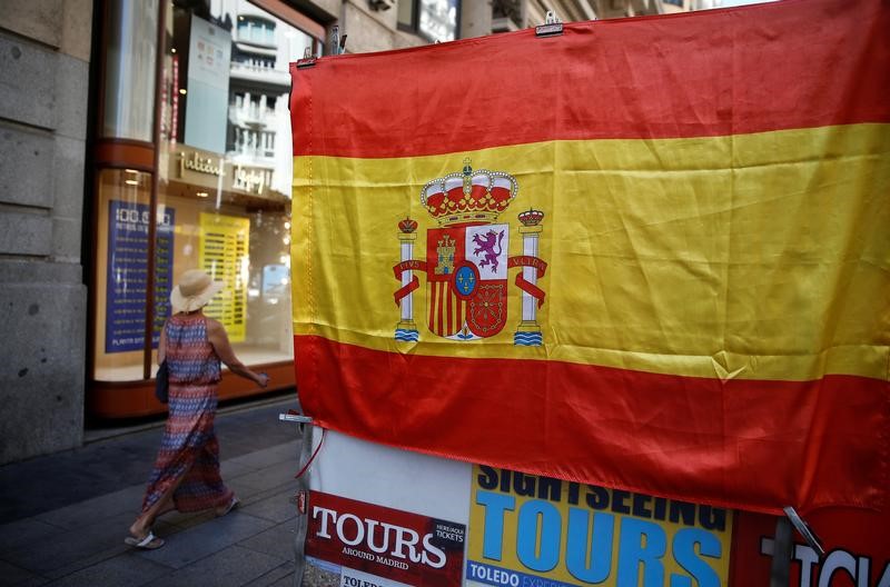© Reuters. A woman walks past a Spanish flag in central Madrid, Spain