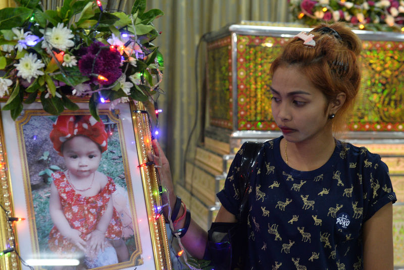 © Reuters. Jiranuch Trirat, mother of 11-month-old daughter who was killed by her father, stands next to a picture of her daughter at a temple in Phuket