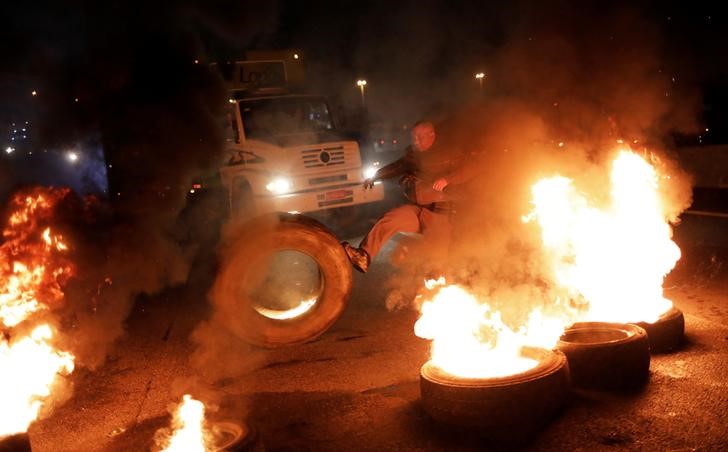 © Reuters. Policial tenta desmontar barricada montada em protesto na Dutra, em São Paulo