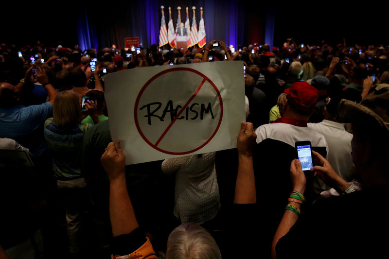 © Reuters. FILE PHOTO: A protester holds up a an anti-racism sign as Republican presidential nominee Donald Trump speaks during a campaign rally in Cedar Rapids