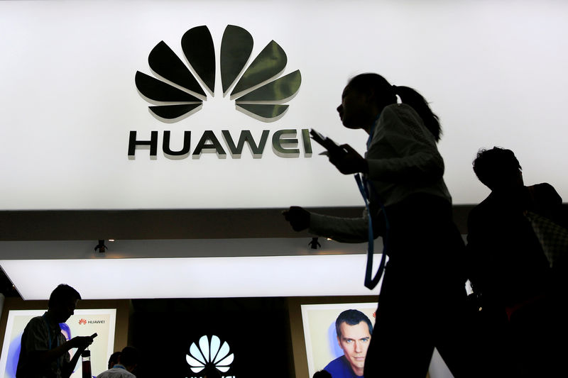 © Reuters. FILE PHOTO: People walk past a sign board of Huawei at CES Asia 2016 in Shanghai