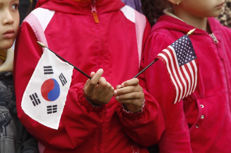© Reuters. FILE PHOTO: A child holds U.S. and South Korean flags prior to the state arrival of South Korean President Lee in Washington