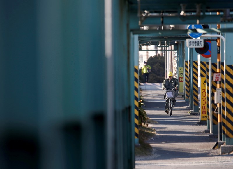 © Reuters. FILE PHOTO: A worker cycles near a factory at the Keihin industrial zone in Kawasaki