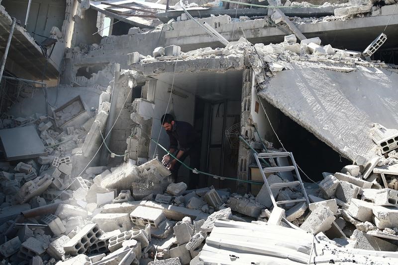 © Reuters. A man removes rubble at a damaged site after airstrikes in the rebel held besieged Douma neighborhood of Damascus