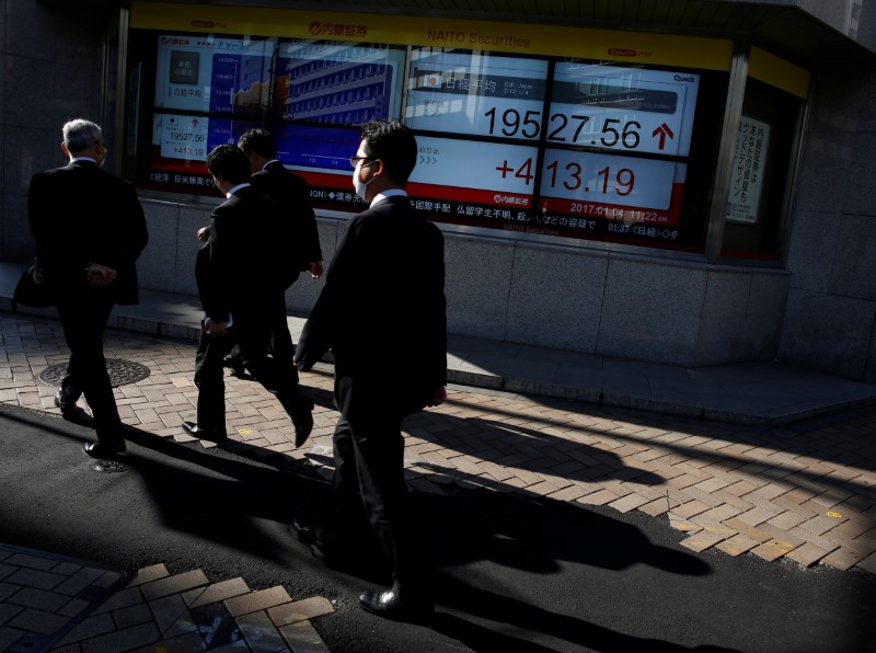 © Reuters. People walk past an electronic board showing stock prices outside a brokerage at a business district in Tokyo