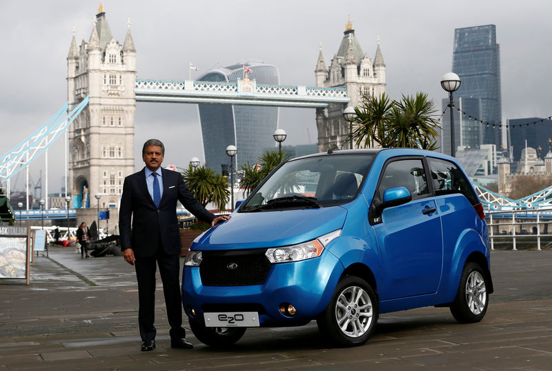 © Reuters. FILE PHOTO: Anand Mahindra, chairman and managing director of Mahindra Group, poses with a Mahindra e2o electric car during its launch in London