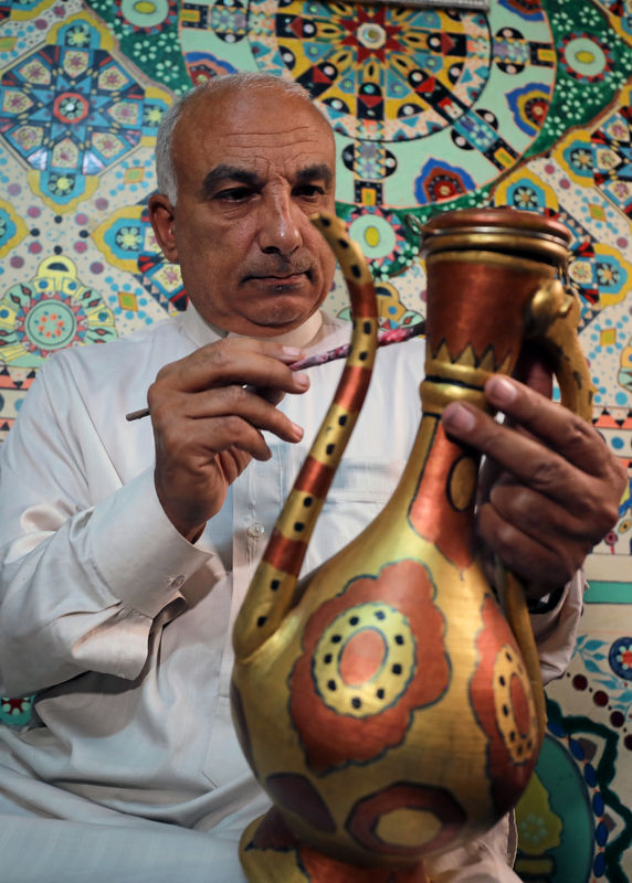 © Reuters. Saad Mohammed paints a copper vase at his studio in the town of Belqina, north of Cairo