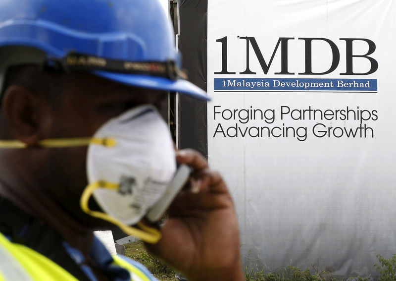 © Reuters. FILE PHOTO - A construction worker talks on the phone in front of a 1Malaysia Development Berhad (1MDB) billboard at the Tun Razak Exchange development in Kuala Lumpur, Malaysia