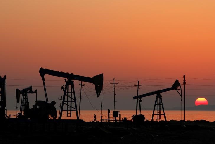 © Reuters. FILE PHOTO: Pump jacks are silhouetted against the rising sun on an oilfield in Baku