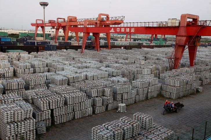 © Reuters. File picture of workers riding on an motor rickshaw through an aluminium ingots depot in Wuxi