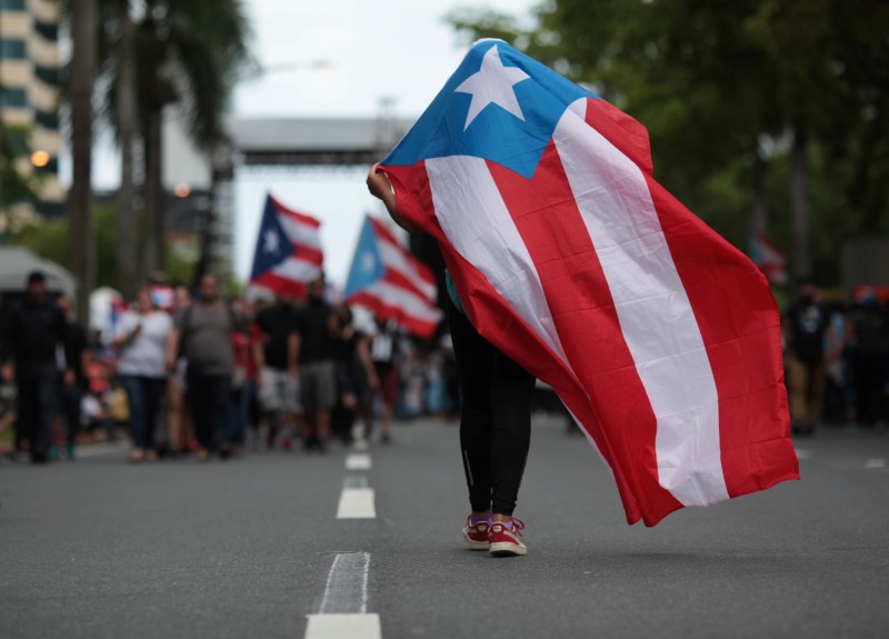 © Reuters. A person carries a Puerto Rican national flag during a protest against the government's austerity measures as Puerto Rico faces a deadline on Monday to restructure its $70 billion debt load or open itself up to lawsuits from creditors, in San Juan